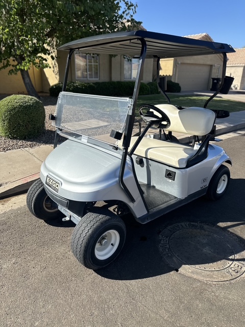 A clean two-seater golf cart parked outdoors