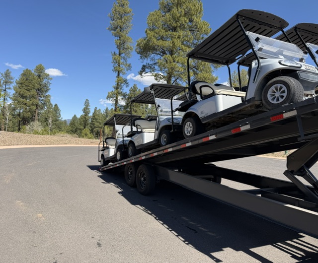 Golf carts loaded on a trailer for transport